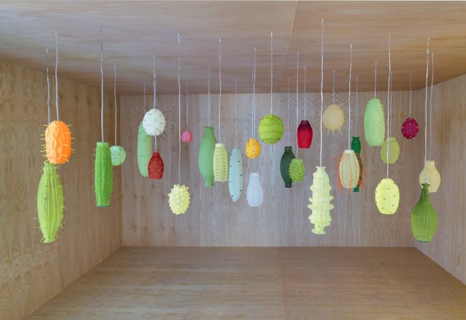 a room with numerous illuminated suspended lights, all loosely reminiscent of tropical fruits