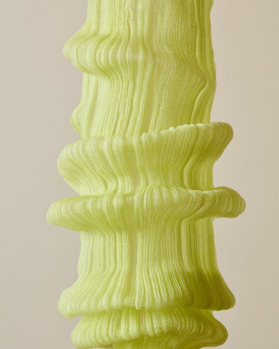 a detail of a suspended green lamp with folds of textile