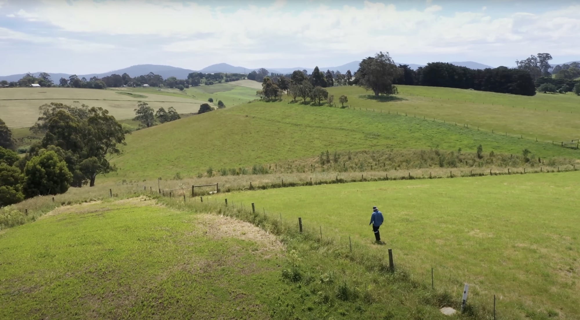 a still from a video showing Beau Miles walking through a field that he is about to plant with trees